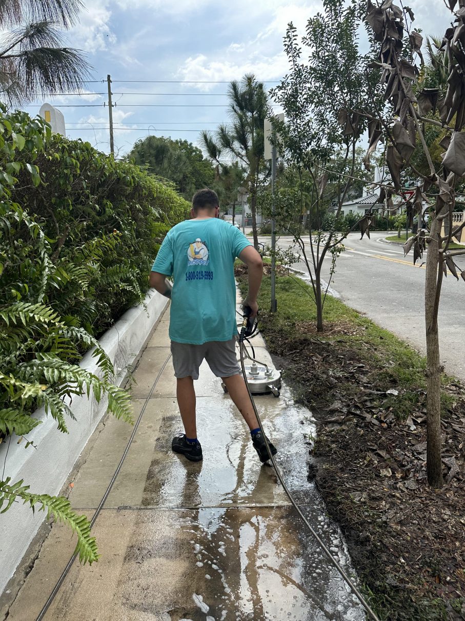Moppey technician pressure washing a Miami walkway with a surface cleaner